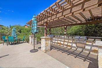 A patio with a pergola and table with umbrellas